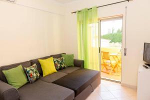 a living room with a couch with yellow and green pillows at TAC - Alcantarilha House in Alcantarilha