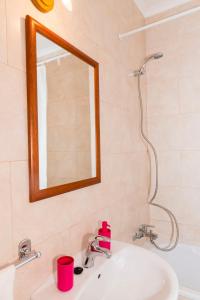 a bathroom with a sink with a mirror and a shower at TAC - Alcantarilha House in Alcantarilha