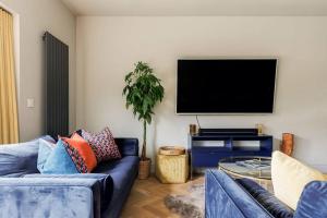 uma sala de estar com um sofá azul e uma televisão de ecrã plano em Luxury, eco-friendly 3 bed haven with plunge pool - Riverway Retreat Lux em Christchurch