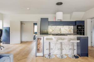 uma cozinha com um balcão com bancos de bar em Luxury, eco-friendly 3 bed haven with plunge pool - Riverway Retreat Lux em Christchurch