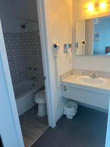 a bathroom with a sink and a toilet and a mirror at Motel Carleton Sur Mer in Carleton sur Mer