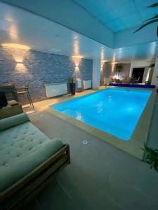 a large swimming pool with a couch in a house at Maison 2 piscines int/ext, spa in Gueugnon