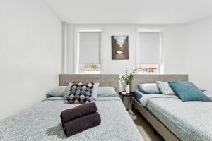 a bedroom with two beds and two windows at Peaceful Apartment in Lower Manhattan New York in New York