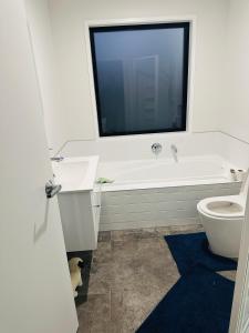 a bathroom with a tub and a toilet and a window at Private Double Room in Christchurch