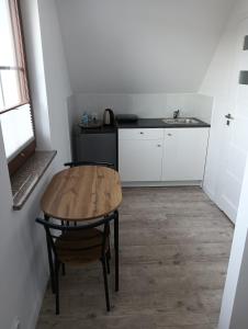 a small kitchen with a wooden table and a sink at Apartamenty przy zamku in Pasłęk
