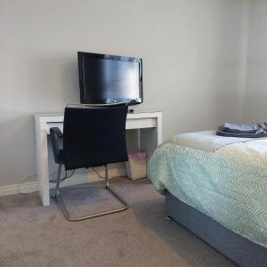 a desk with a television and a chair next to a bed at Lawnbrook Town House in Belfast