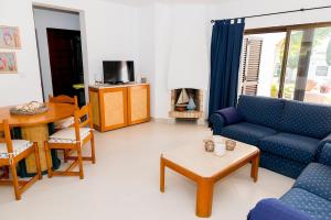 uma sala de estar com um sofá azul e uma mesa em The Albufeira Concierge - Villa Praia São Rafael em Albufeira