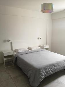 a white bedroom with a bed and two night stands at Lykavitos Apartments in Nicosia