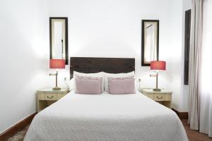 エル・ロシオにあるHospedarte Arenas de El Rocioのベッドルーム(白い大型ベッド、ランプ2つ付)