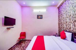 - une chambre avec un grand lit et une chaise rouge dans l'établissement Shri Radhe Krishna Bhawan, à Lucknow