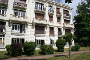 ein weißes Gebäude mit Balkonen und Büschen davor in der Unterkunft Hermite au Touquet in Le Touquet-Paris-Plage