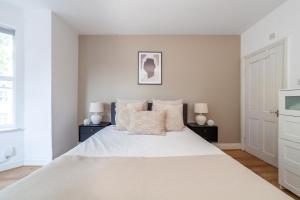 una camera bianca con un grande letto bianco con due lampade di The Wood Green Collection a Londra
