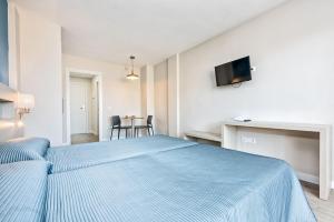 a bedroom with a blue bed and a tv on the wall at Veramar Aparthotel in Fuengirola