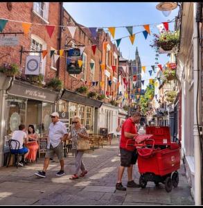 a man pushing a red cart down a city street at 2 bed coach house flat Hereford in Hereford +9 photos