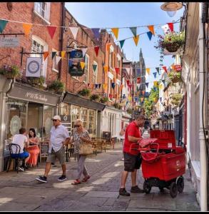 a man pushing a red cart down a city street at 2 bed coach house flat Hereford in Hereford