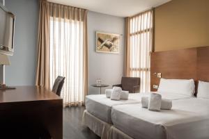 a hotel room with two beds and a desk at Hotel Madanis in Barcelona