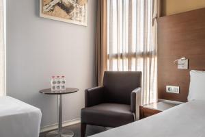 a hotel room with a chair and a table at Hotel Madanis in Barcelona