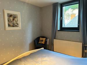 een slaapkamer met een bed, een raam en een stoel bij Le Reflet Meuse in Dinant