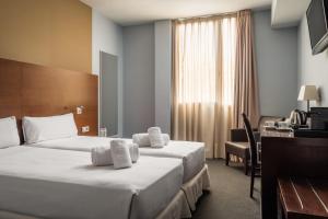 ロスピタレート・デ・リョブレガートにあるホテル マダニスのベッド2台とデスクが備わるホテルルームです。