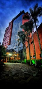 a large building with palm trees in front of it at Swan Novo Hamburgo in Novo Hamburgo