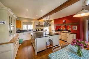 uma grande cozinha com paredes vermelhas e armários brancos em Ivy Farm 8 em Grimston