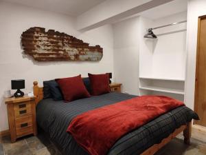 a bedroom with a bed with red pillows on it at Kempies-Cozy house on the NC500 in Durness