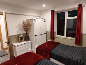 a bedroom with two beds and a window with red curtains at Kempies-Cozy house on the NC500 in Durness
