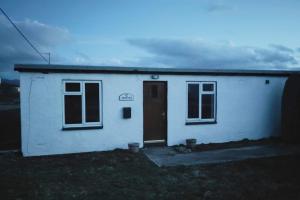 uma pequena casa branca com uma porta e janelas em Kempies-Cozy house on the NC500 em Durness