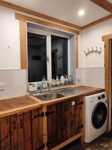 a kitchen with a sink and a washing machine at Kempies-Cozy house on the NC500 in Durness