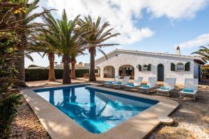 una piscina con sedie e palme di fronte a una casa di Villa Bini Yaya - Cap den Font a Sant Lluís