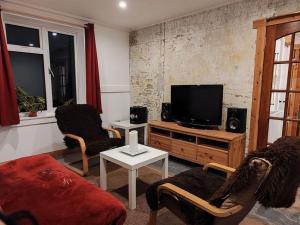 a living room with two chairs and a flat screen tv at Kempies-Cozy house on the NC500 in Durness