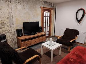 a living room with two chairs and a flat screen tv at Kempies-Cozy house on the NC500 in Durness