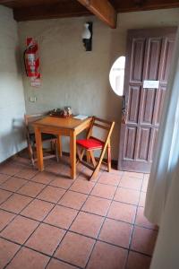 een kamer met een tafel, een stoel en een deur bij De Luna in Puerto Pirámides