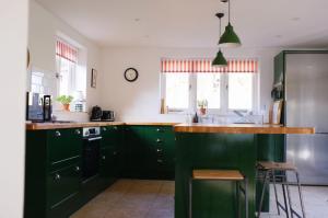 a kitchen with green cabinets and a stainless steel refrigerator at Keepers Cottage F in Bircham Newton
