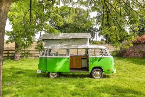 an old green van parked in a field at eDub Indie - The 100% Electric Classic Camper in Great Ouseburn