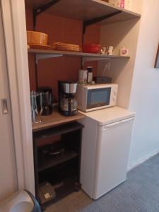 una pequeña cocina con microondas y nevera. en Chambre indépendante, en Replonges