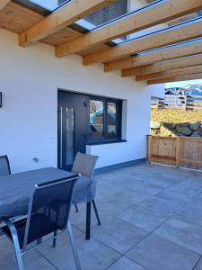 un patio con mesa, sillas y techo de madera. en Ferienwohnung Abenthung en Grinzens