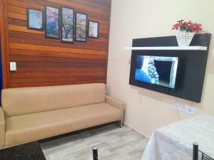 Zimmer mit Sofa und TV an der Wand in der Unterkunft Casa Colonial em Guaratuba, próximo a praia in Guaratuba