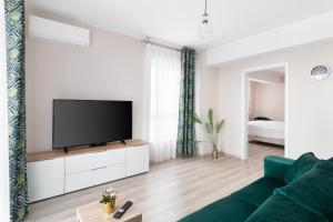 un salon avec un canapé vert et une télévision à écran plat dans l'établissement Blissful Haven Flats, à Oradea