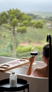una mujer en una bañera sosteniendo una copa de vino en Jardim das Pedras en Bom Jardim da Serra