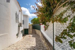 an alley with white buildings and a tree at TAC - Vila Tina Vilamoura in Quarteira
