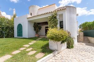 a white house with a green door and a yard at TAC - Vila Tina Vilamoura in Quarteira