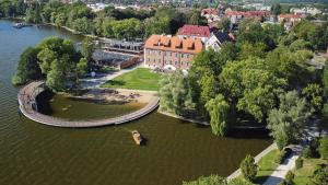 a boat in the water in front of a building at Loft Amalia w wieży strażackiej, butikowy, blisko jeziora in Szczecinek