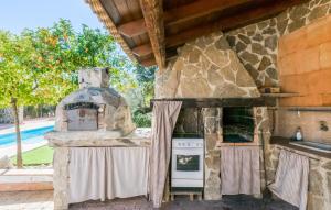 an outdoor kitchen with a stone wall and an oven at 3 Bedroom Awesome Home In Casariche in Casariche