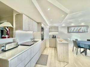 a kitchen with white cabinets and a blue table at Vezelay, by Welcome to Cannes in Cannes