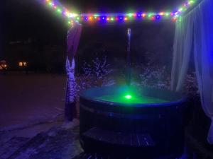 bañera de hidromasaje con luz verde y luces de Navidad en Classic Latvian Sauna and Hot Tub in a quiet place, en Mālpils