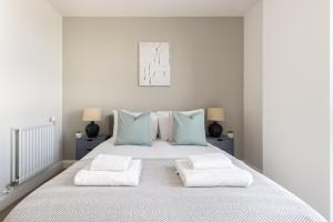 a white bedroom with a large white bed with blue pillows at The Bow Flats in London