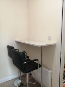 a desk with a black chair and a white table at Cosy City Apartment in Cork