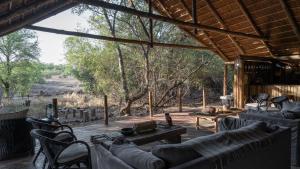 un soggiorno con divani, tavolo e sedie di Mashatu Tent Camp a Lentswelemoriti