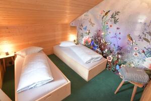 2 Betten in einem Zimmer mit einer Wand mit Blumen in der Unterkunft Casa Fausta Capaul in Brigels